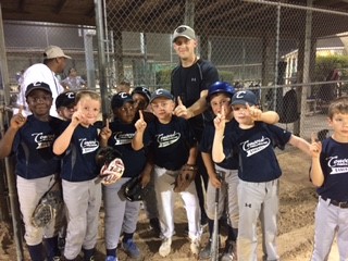 Youth Baseball team huddled around Coach putting up number 1 